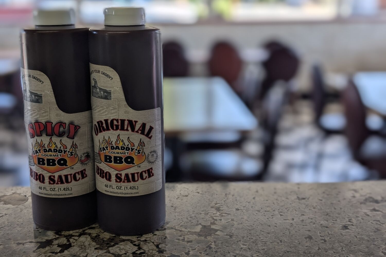 Fat Daddy's Original and Spicy BBQ sauce squeeze bottles on the counter, dining room behind